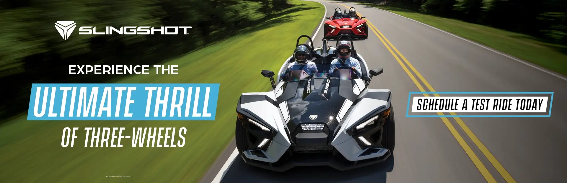 A white and a red Slingshot driving down a highway. Experience the ultimate thrill of three-wheels. Schedule a test ride today.