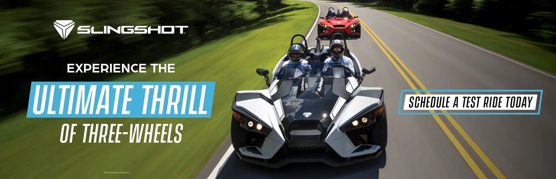 A white and a red Slingshot driving down a highway. Experience the ultimate thrill of three-wheels. Schedule a test ride today.