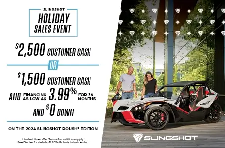 A man and woman are looking down at a Slingshot Roush edition. With a promotion of $2,500 customer cash or $1,500 customer cash and 3.99% for 36 months and $0 down with the purchase of a 2024 Slingshot Roush Edition.