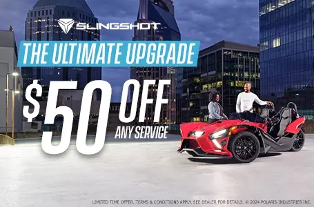 A man and a woman standing next to a red slingshot in an empty lot. Promotional Offer: The ultimate upgrade. $50 off any service.