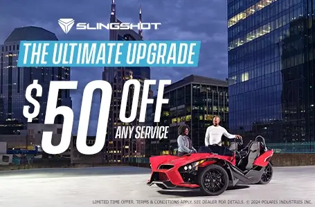 A man and a woman standing next to a red slingshot in an empty lot. Promotional Offer: The ultimate upgrade. $50 off any service.