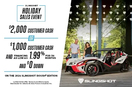 A man and woman are looking down at a Slingshot Roush edition. With a promotion of $2,000 customer cash or $1000 customer cash and 1.99% for 36 months and $0 down with the purchase of a 2024 Slingshot Roush Edition.